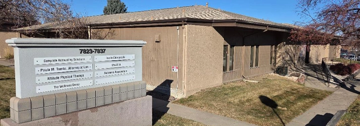 Exterior view of a tan commercial office building with a sidewalk and lawn