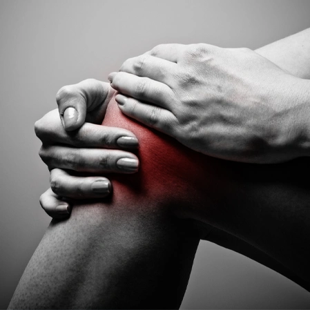 Hands holding a knee highlighted in red to illustrate pain or inflammation