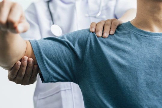 Physician assisting a patient with a shoulder mobility assessment