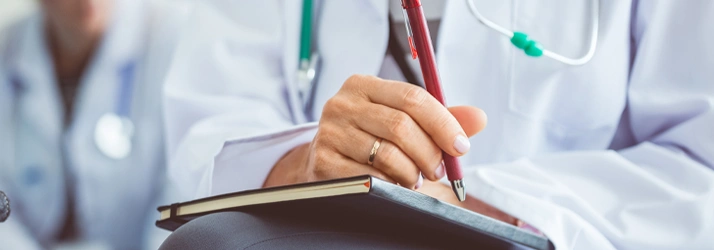 Close-up of a healthcare professional writing in a notebook