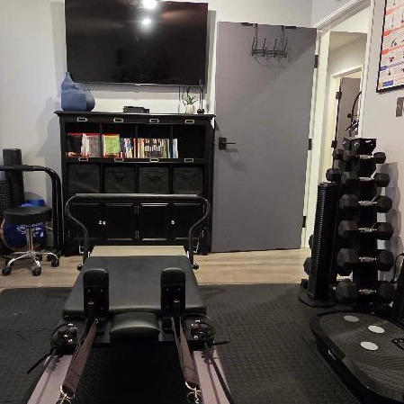 Rehabilitation room with a reformer exercise machine in the foreground,