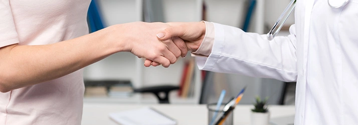 Close-up of a doctor in a white coat shaking hands